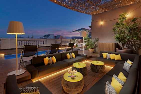 En terrass med moderna möbler, en pool och belysning vid skymning. (AI-genererad text)