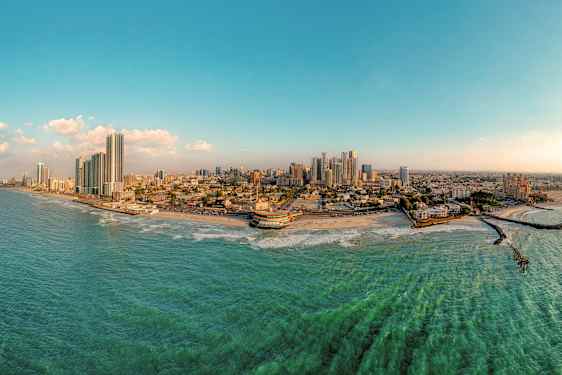 Panoramabild av en kuststad med höghus, strand och hav. (AI-genererad text)
