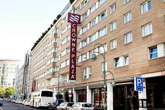 Crowne Plaza-hotellbyggnad med parkeringsskylt och buss framför. (AI-genererad text)