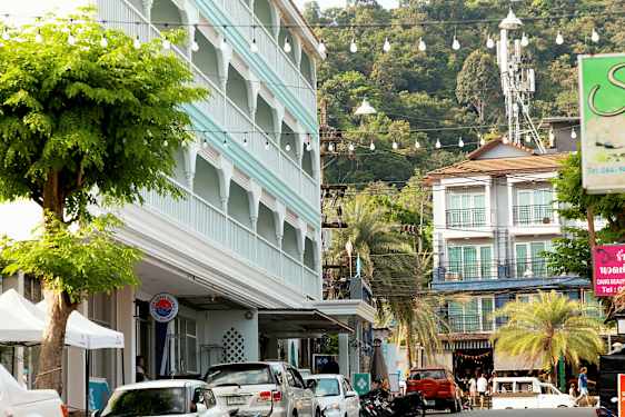 Gatuvy med parkerade bilar, en byggnad med blå fasad och grönskande träd. (AI-genererad text)