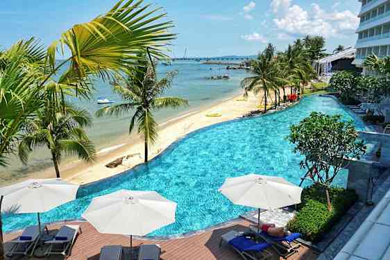 En strand med palmer och en pool i förgrunden. (AI-genererad text)