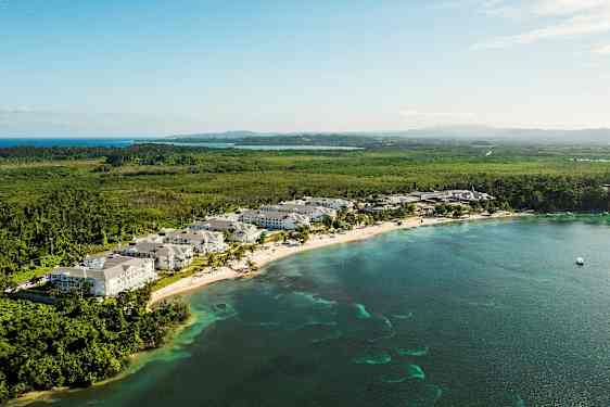 Utsikt över en kuststräcka med semesteranläggning, omgiven av grönska och hav. (AI-genererad text)