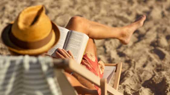 Man läser bok i solstol på strand