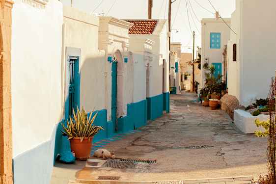 En moppe står parkerad i en gränd mellan vitkalkade hus.