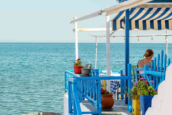 Kvinna sitter på restaurang vid havet på Samos