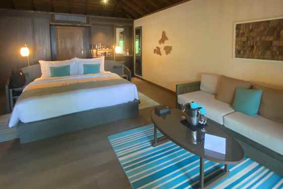 Villa inifrån med stor säng loungegrupp och detaljer i turkost