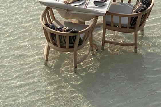 Dukat bord med två stolar stående i havet