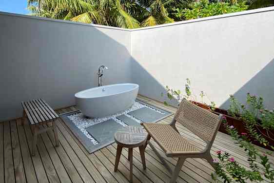 Utomhus badrum med badkar och loungegrupp och palmer