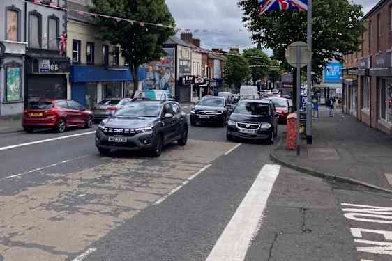 Gata med bilar och Storbritanniens flagga på en lyktstolpe.