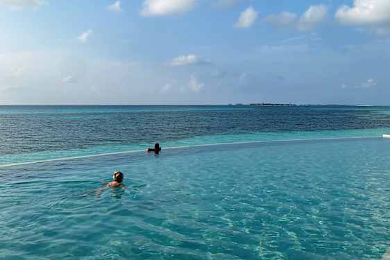 Två personer simmar i infinitypool ut mot havet