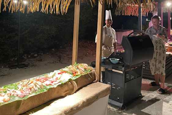 Kock vid grill på stranden på kvällen
