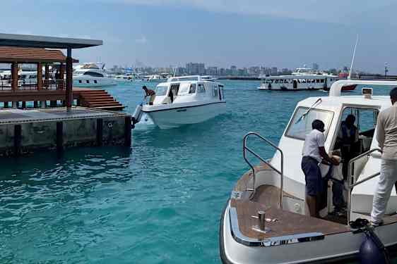Hamn med flera speedboats. Males silhuet i bakgrunden.