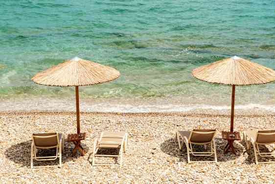 Solstolar och parasoll på stenstrand