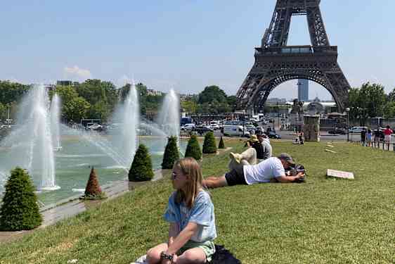 Flicka på gräsmatta framför Eiffeltornet