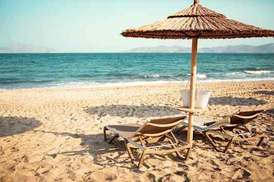 Strand och solstol med parasoll