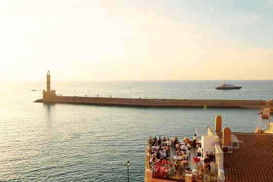 Restaurang i hamnen i Chania med fyren i bakgrunden