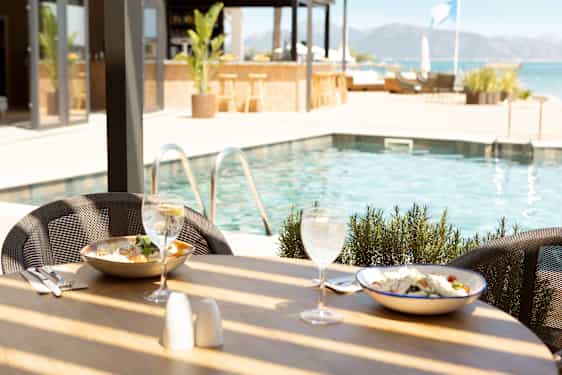Uppdukade tallrikar på ett bord framför en pool på Sunprime Pollensa Bay på Mallorca