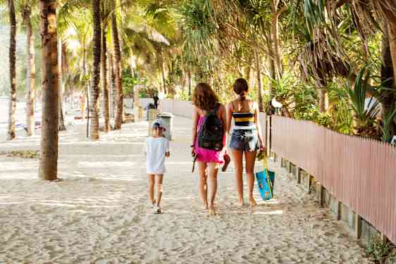 Tre barn som går på stranden i Thailand