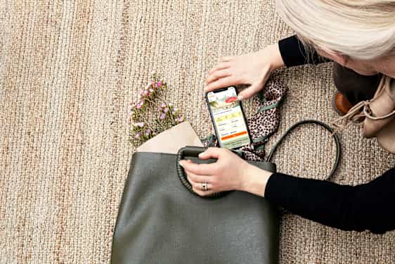 Kvinna lägger ner en mobil i sin väska