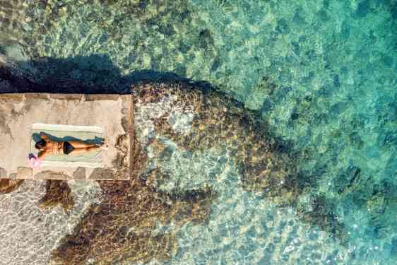 kvinna solar vid havet i Kroatien