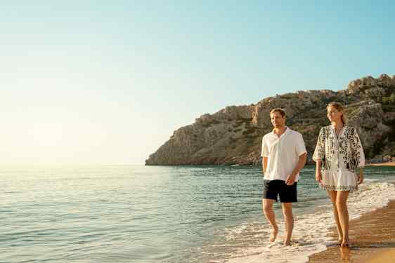 Ett par går i vattenbrynet på en strand
