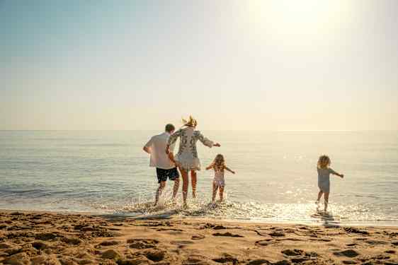 Familj hoppar i vattnet från stranden
