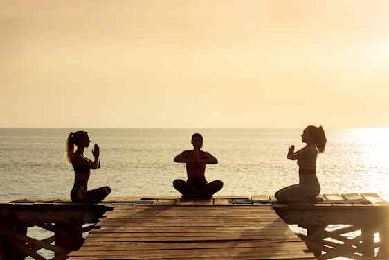 Yoga på brygga i solnedgång