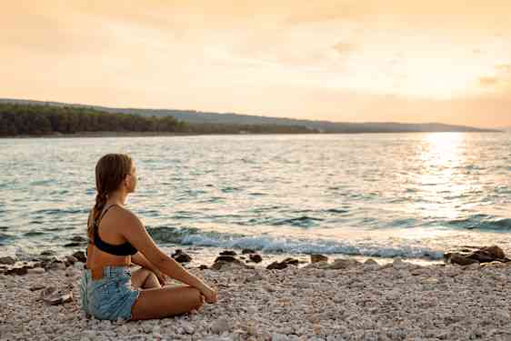 Kvinna njuter av solnedgången på en strand i Kroatien