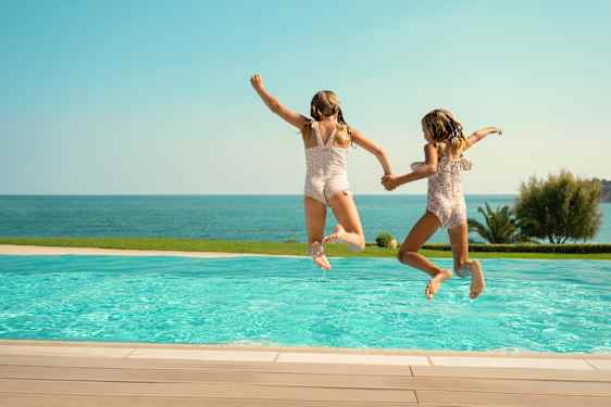 Barn hoppar ner i en pool
