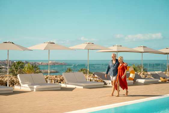 Par går längs med en pool på ett hotell