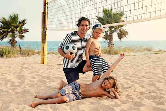 Familj spelar vollyboll på stranden