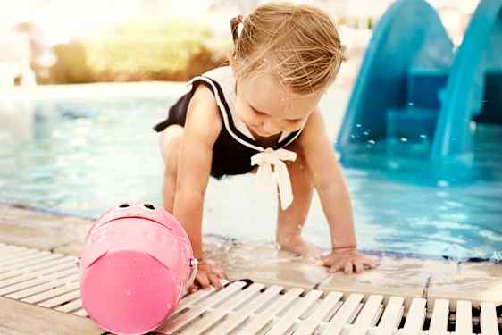 Flicka leker med en hink vid poolkanten