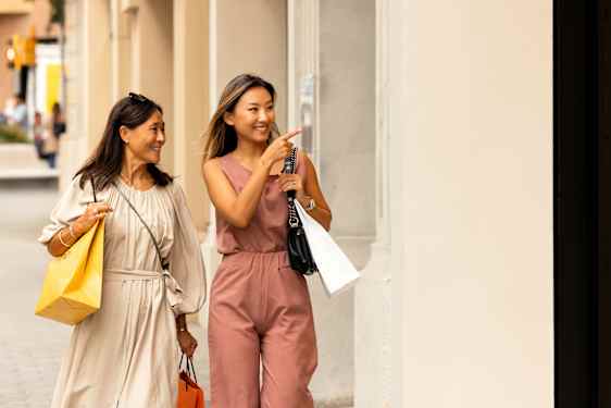 Två kvinnor med shoppingpåsar på gata i Barcelona