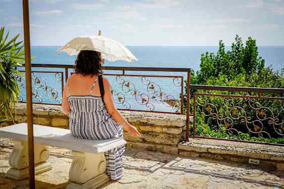 Kvinna under parasoll tittar ut över vattnet