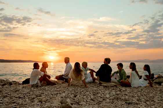Grupp på strand i solnedgång