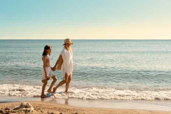Mamma och dotter går på en strand