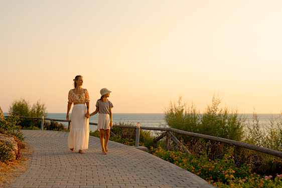 En kvinna går med ett barn med havet som bakgrund.