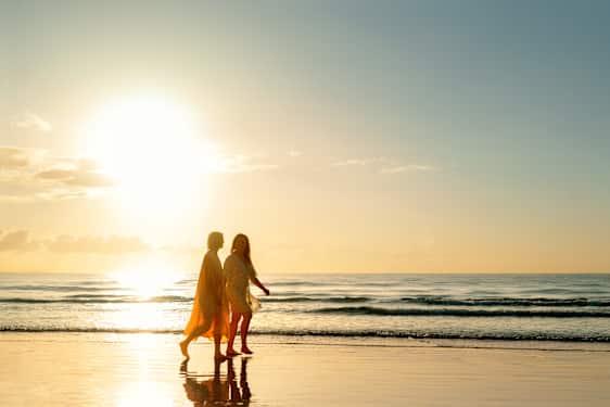 Kvinnor promenerar på strand i solen