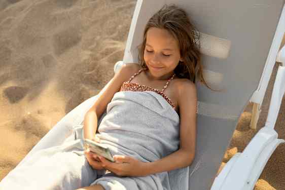 Flicka med telefon på solstol