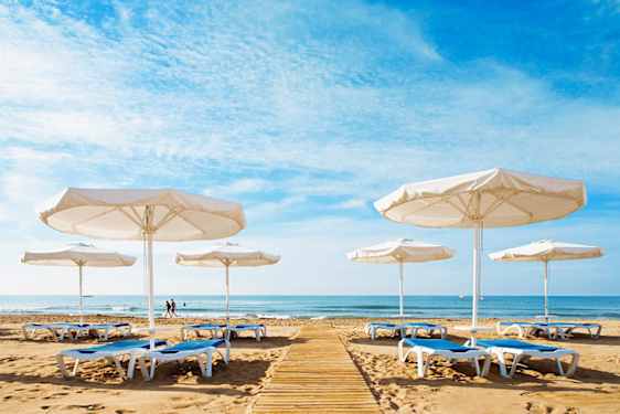 Strand med solstolar och parasoller