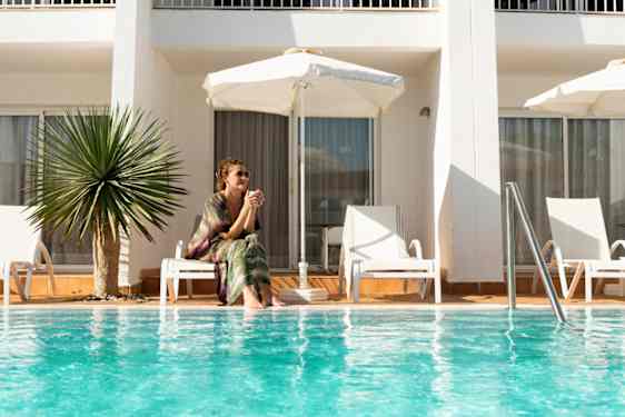 Kvinna sitter vid poolen på ett hotell