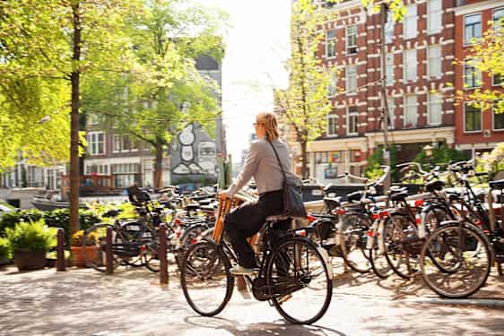 Kvinna cyklar på en gata i Amsterdam