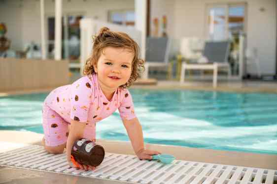 Lille pige leger med spand ved poolen