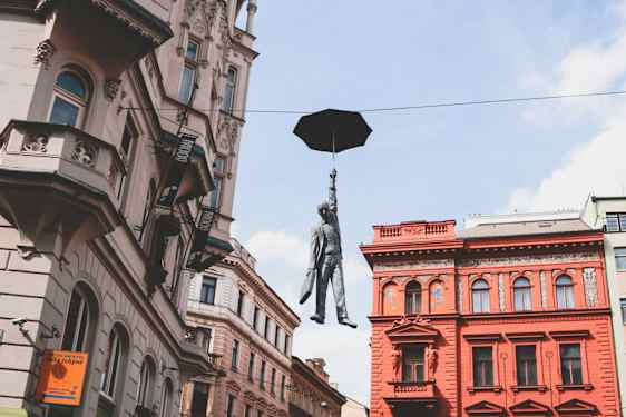 Skulptur av en man som hänger i ett paraply i Prag. Foto: Nastya Dulhiier, Unsplash