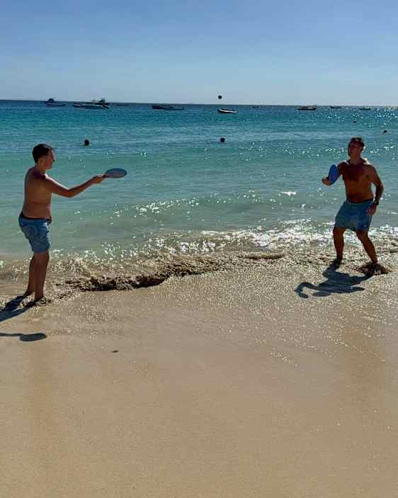 Lek på stranden, två män spelar strandtennis