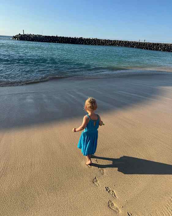 En flicka går på stranden – hennes fotspår är de enda som syns.