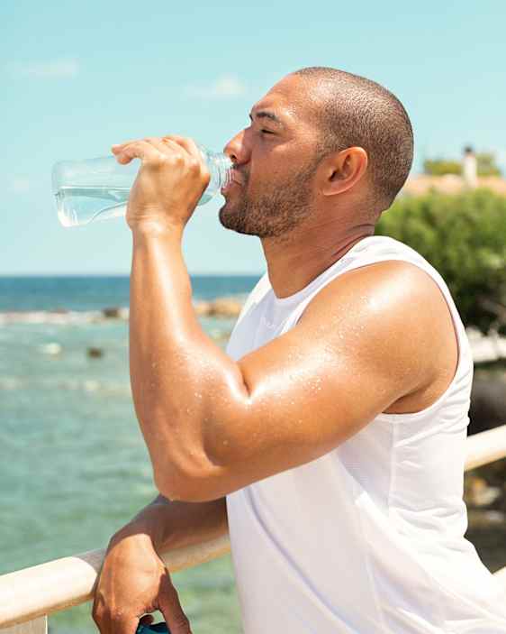 Man dricker vatten vid stranden