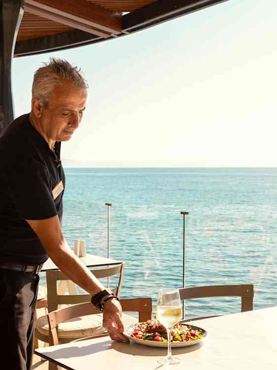 Servitör serverar mat på en restaurang vid havet