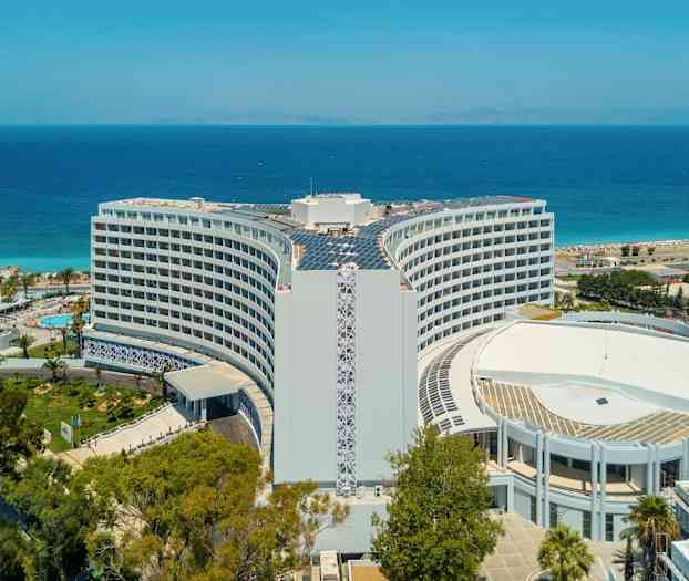 Hotellet med havet och stranden i bakgrunden. (AI-genererad text)