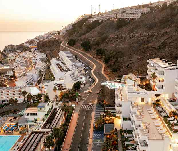Vy över hotell och sluttning vid kusten, med havet i bakgrunden. (AI-genererad text)
